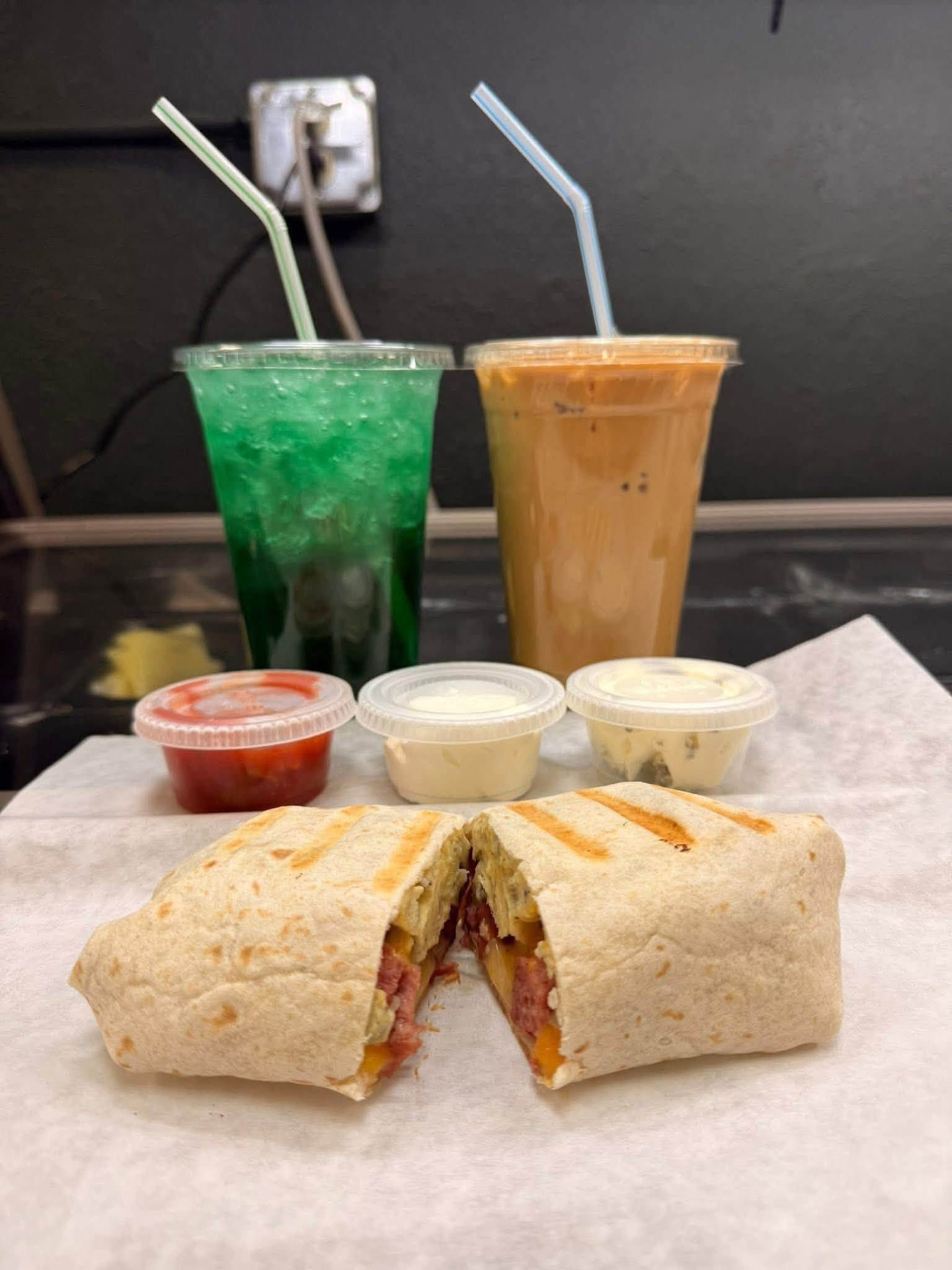 Grilled breakfast wrap with dipping sauces and drinks